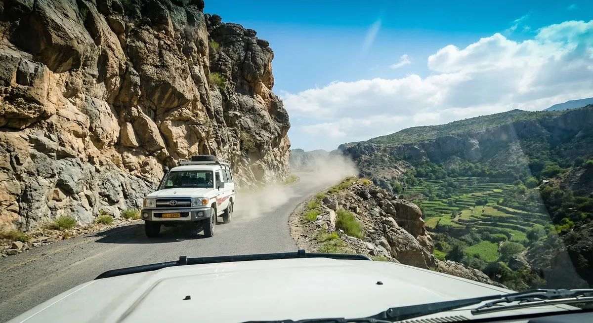 White 4x4 Toyota Land Cruiser driving the mountain road to Jebel Akhdar Oman with valley view below